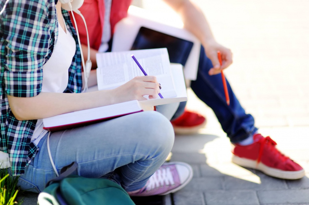 Close up photo of young happy students with books and notes outdoors